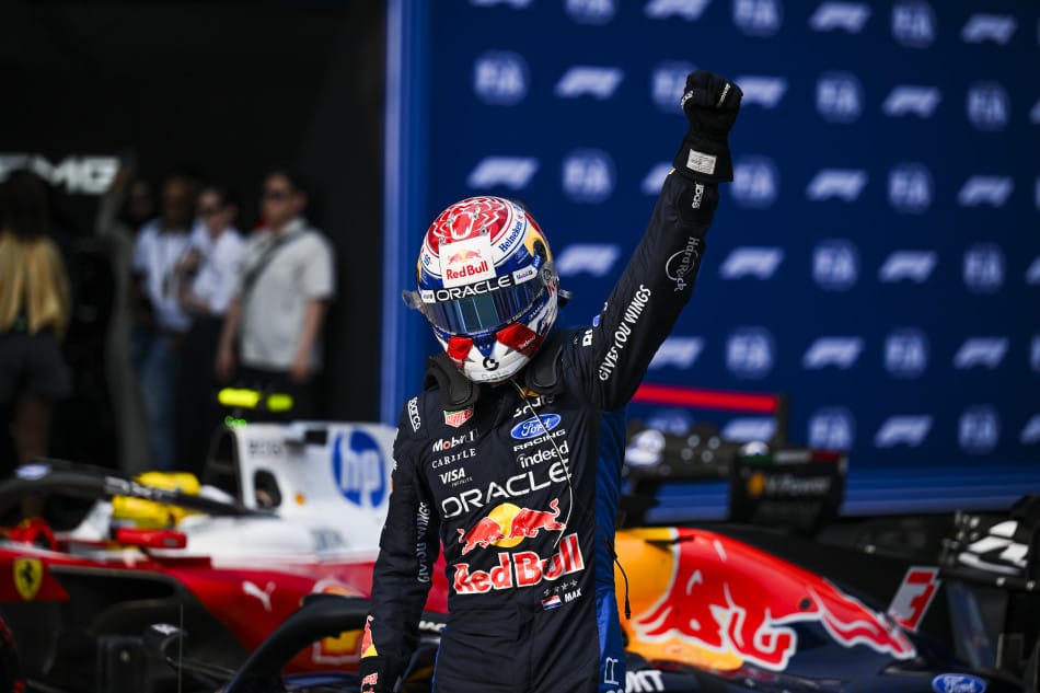 Max Verstappen, con el casco puesto, levanta el puño junto a su Red Bull tras lograr la pole