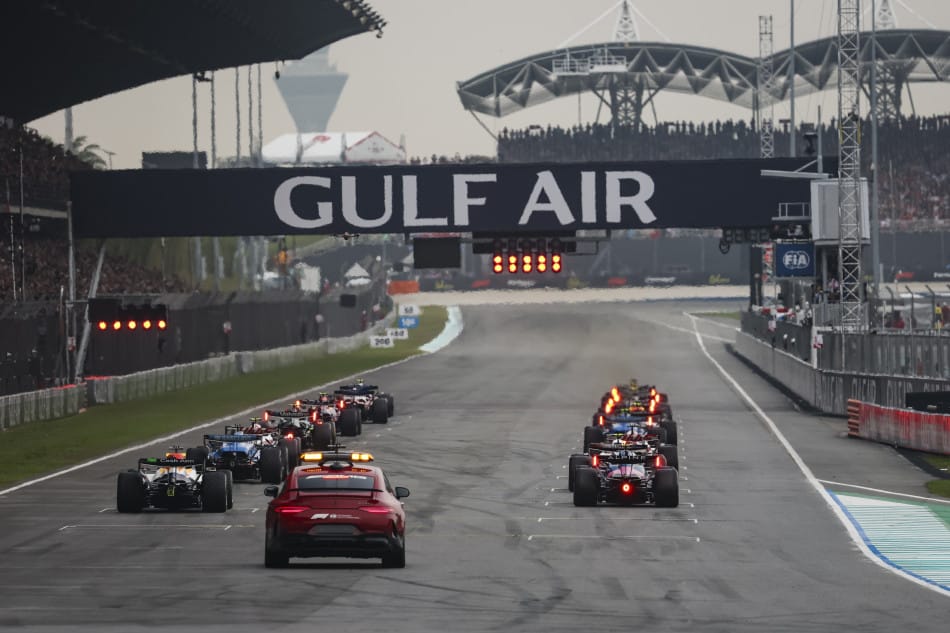 Los monoplazas detenidos en la parrilla de Sepang detrás del coche de seguridad, con el semáforo en rojo