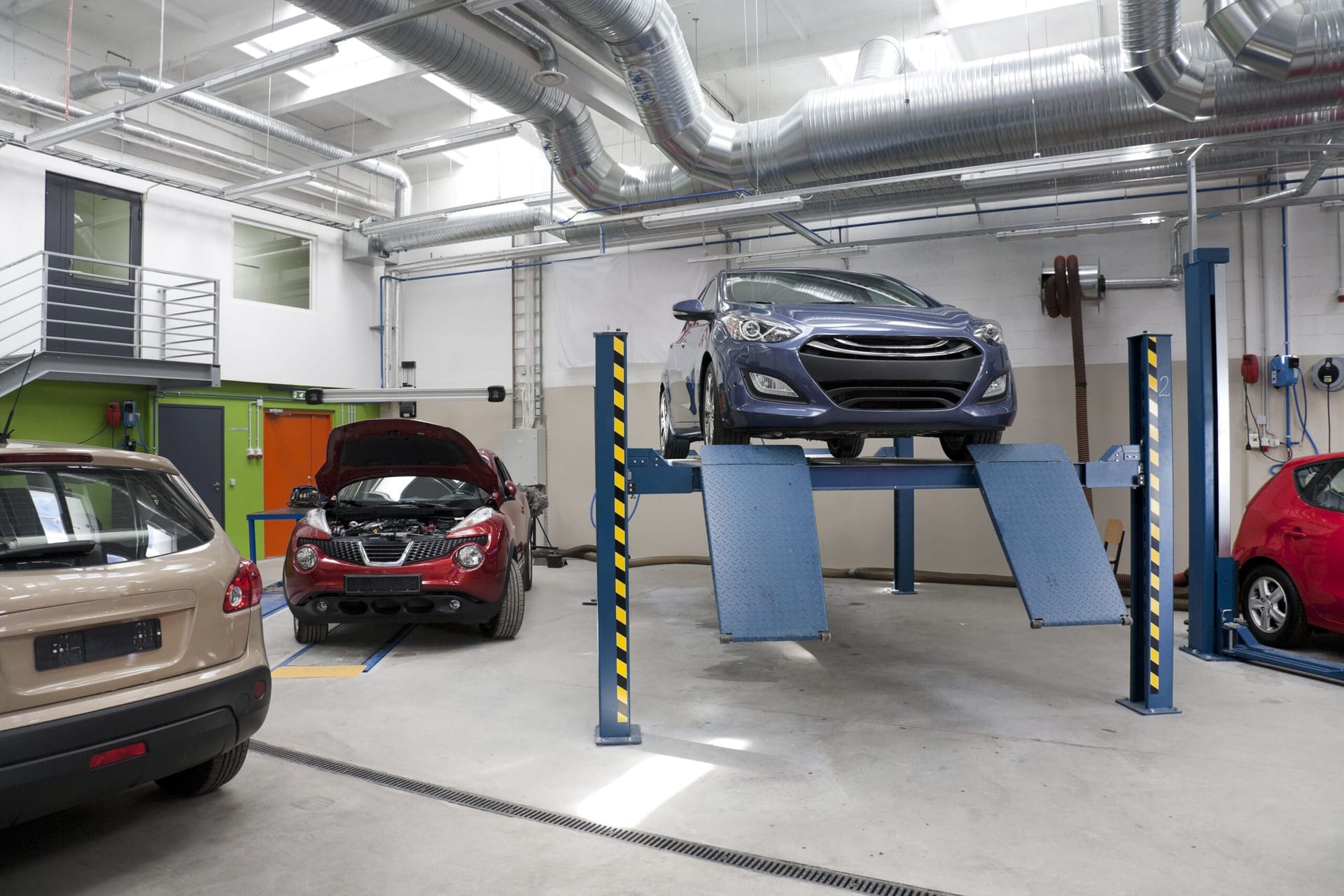 Varios coches en un taller, uno de ellos sobre un elevador