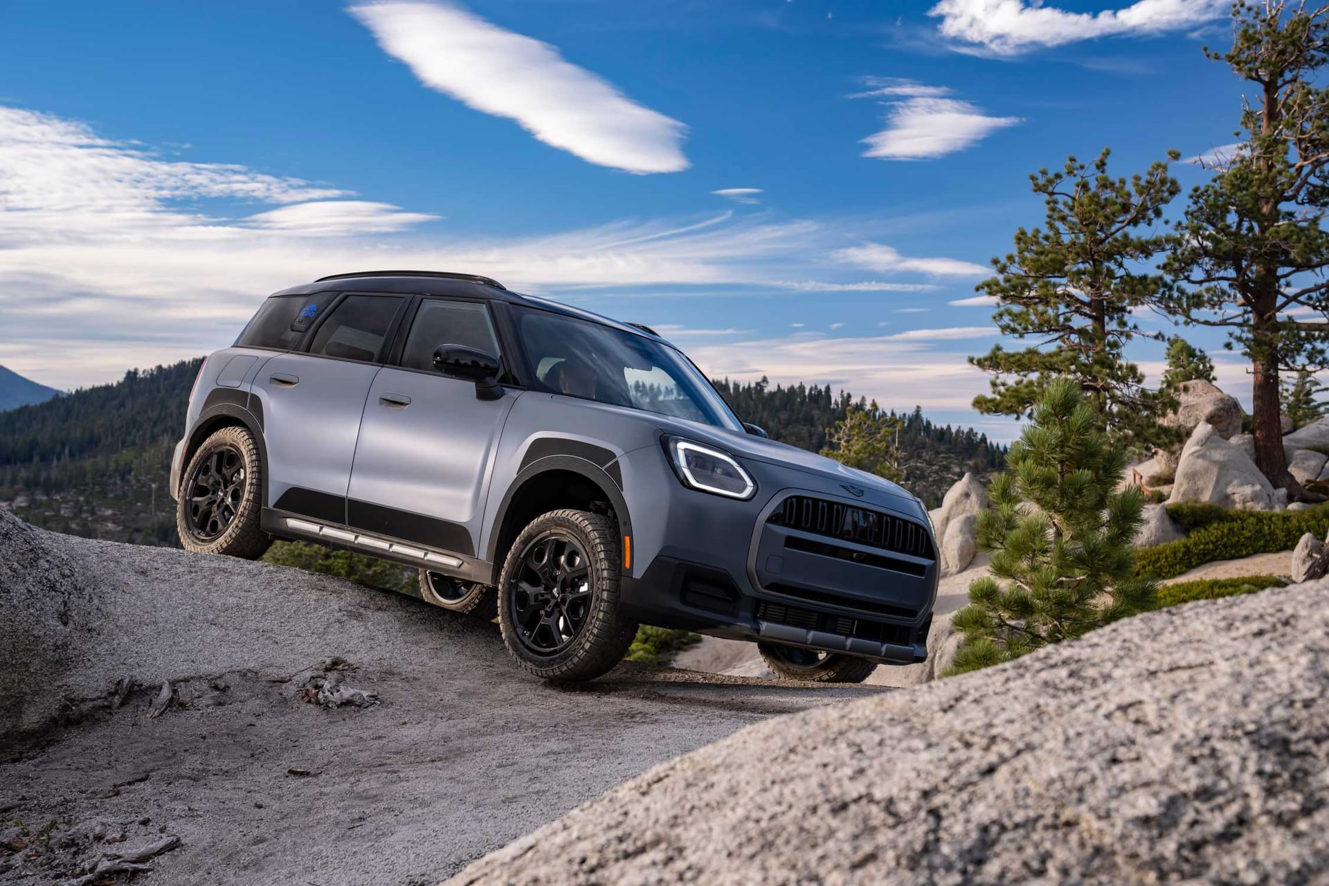 El MINI Countryman Untamed Edition gris azulado sobre una roca entre pinos