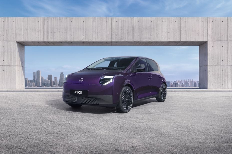 Un Nissan Pixo eléctrico morado aparcado bajo una estructura de hormigón, con una ciudad al fondo