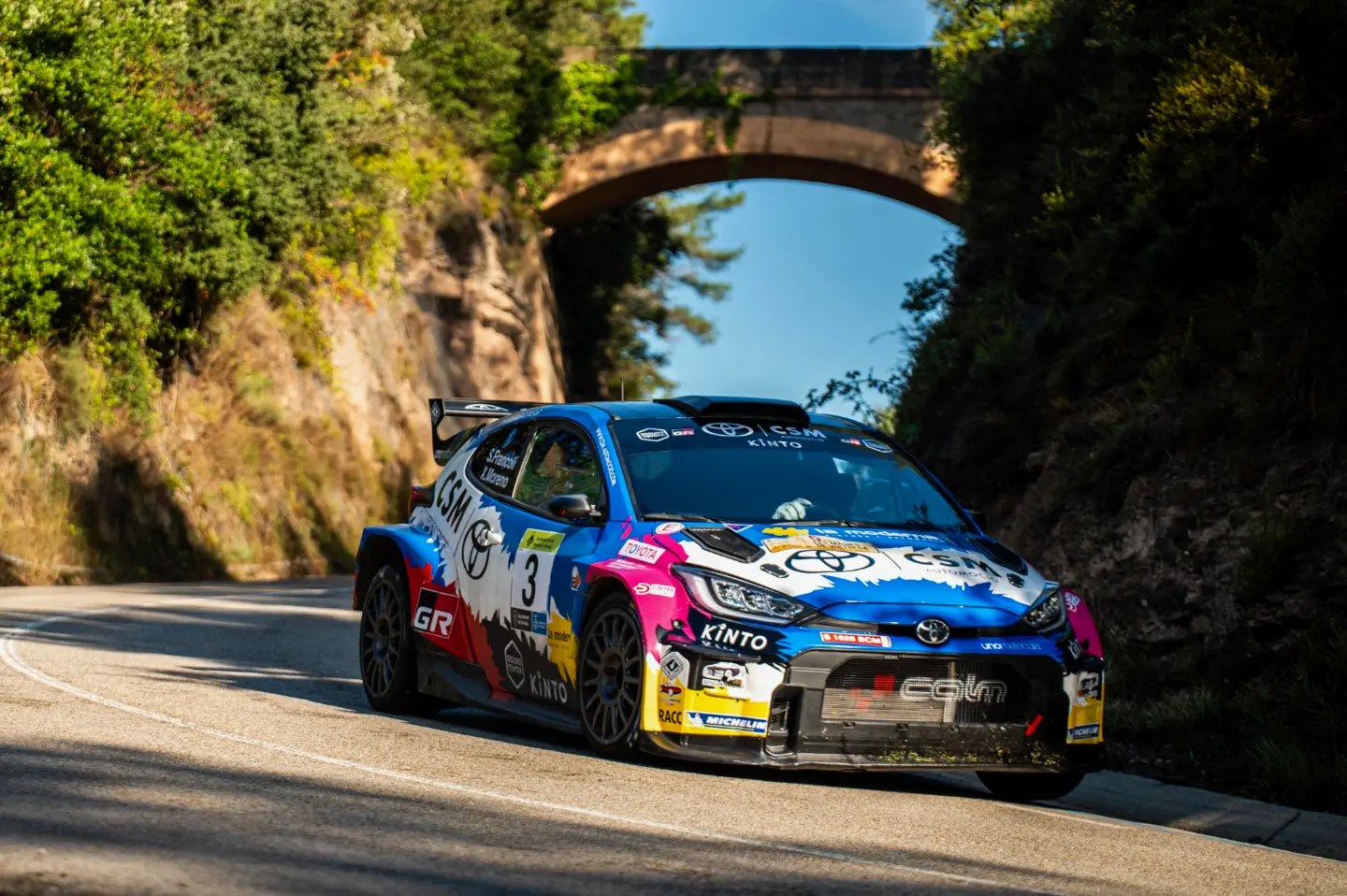 El Toyota GR Yaris Rally2 número 3 de Sergi Francolí y Xevi Moreno toma una curva bajo un puente de piedra