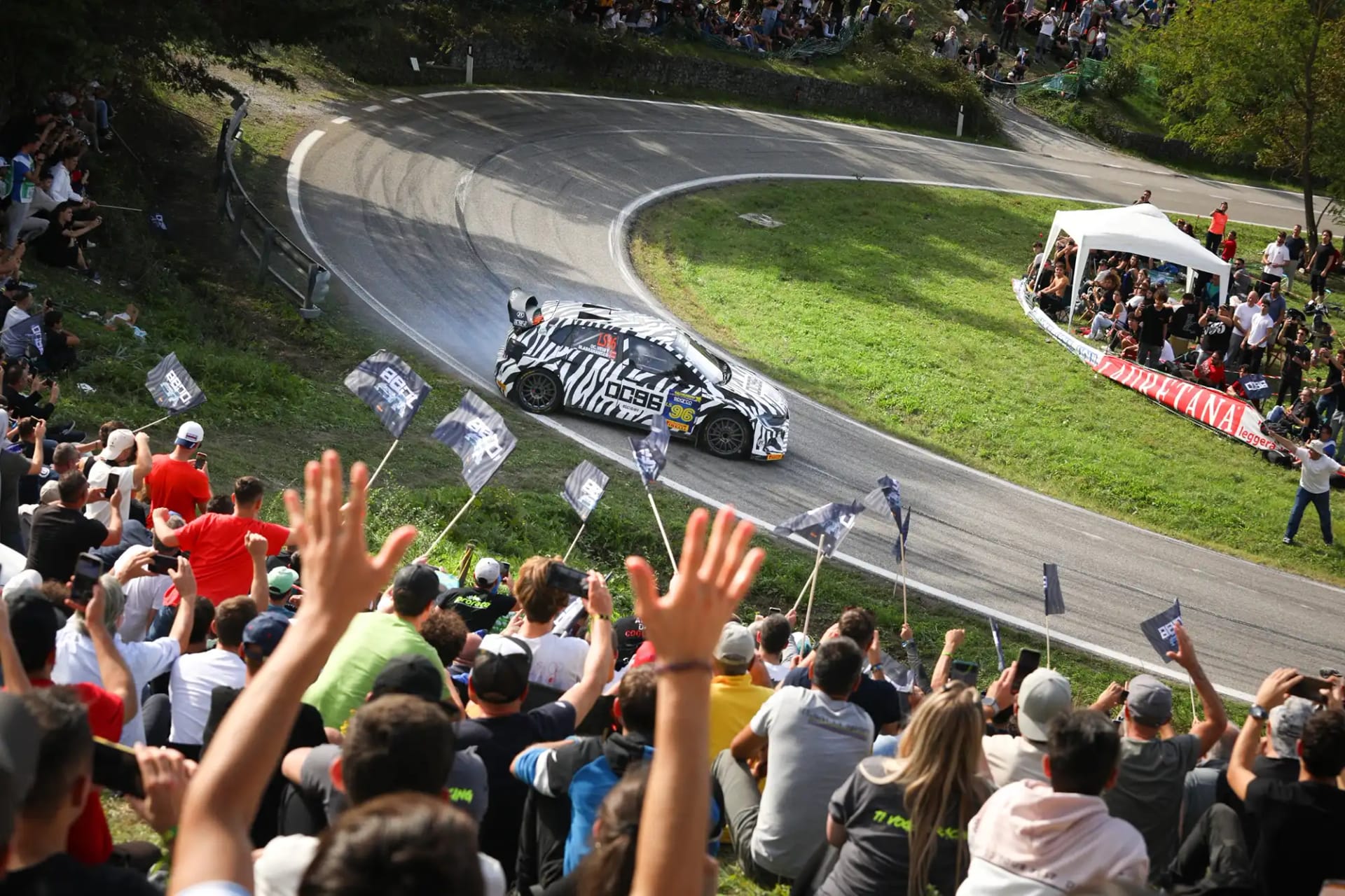Aficionados saludan el paso de un coche de rallies por una horquilla en San Marino