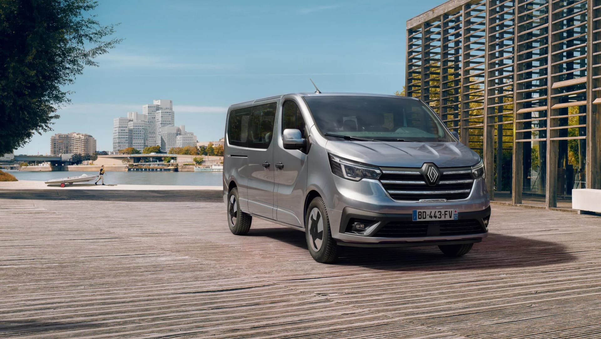 Un Renault Trafic de pasajeros gris aparcado junto a un edificio de cristal
