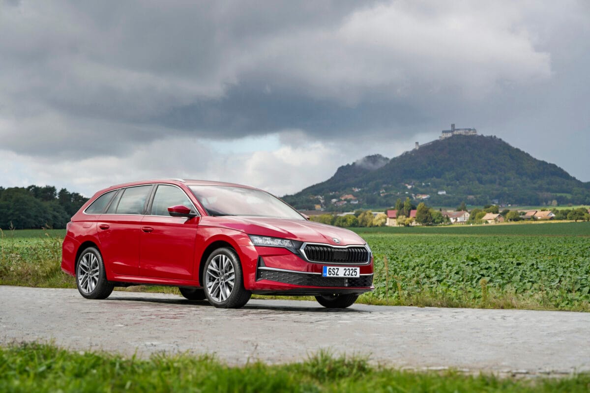 Un Škoda Octavia familiar de color rojo en una carretera rural, con una colina al fondo