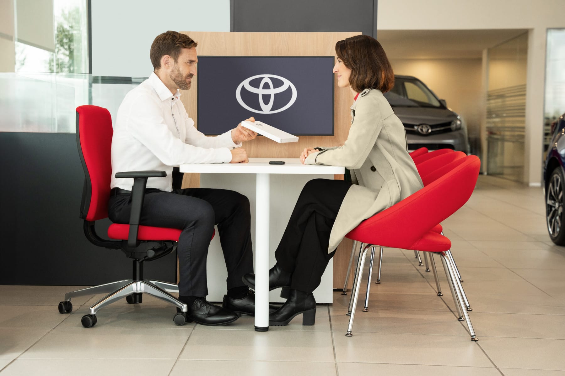 Un asesor de un concesionario Toyota entrega documentación a una clienta en la sala de exposición