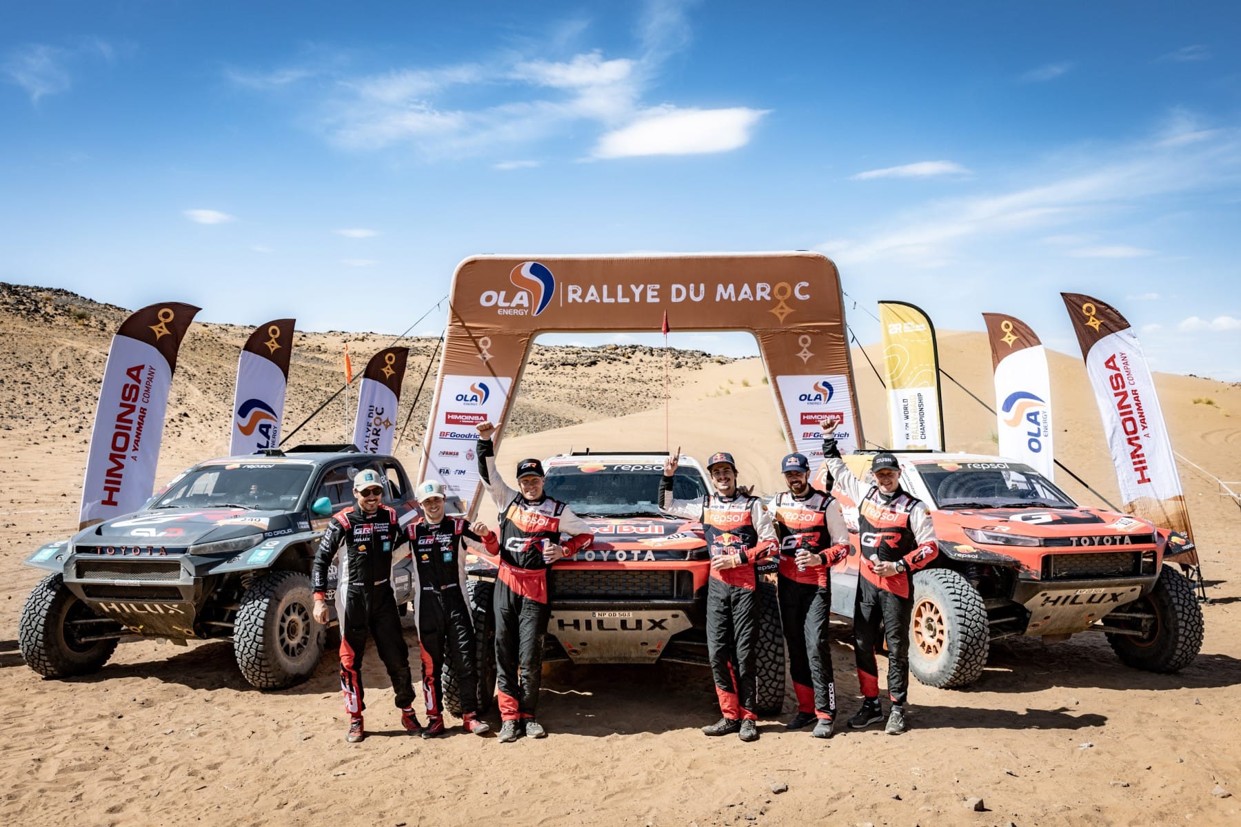 Los tres Toyota Hilux del podio y sus tripulaciones bajo el arco de meta del Rallye du Maroc